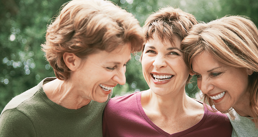 Three women share a laugh and show off their dentures